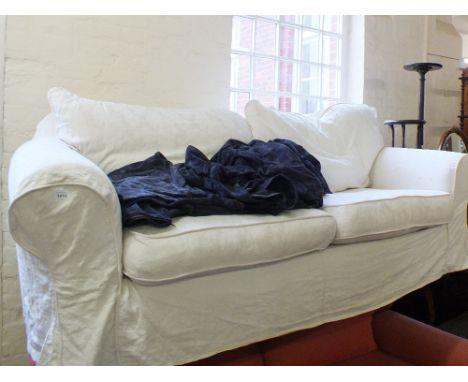 A modern white three seat sofa with white loose covers and additional blue loose cover