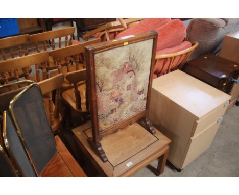 A 1930's oak framed and embroidered firescreen decorated with a country cottage 
