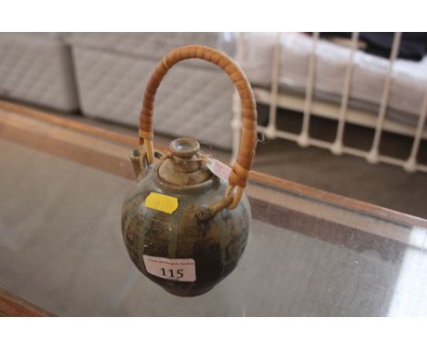 An oriental pottery teapot with wicker swing handle stamped to base