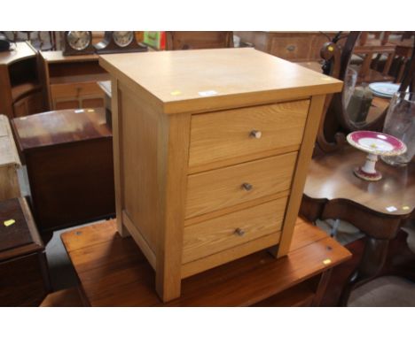 A light oak three drawer bedside chest