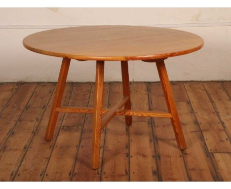An Ercol pine circular dop-leaf dining table, raised on square cut supports united by an X-framed stretcher, width 115cm