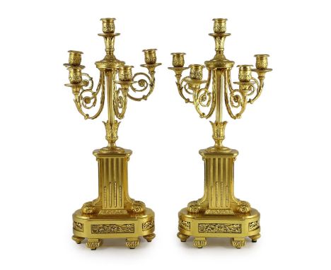 A pair of 19th century French ormolu five light candelabra, with foliate scroll branches and stepped architectural bases, one