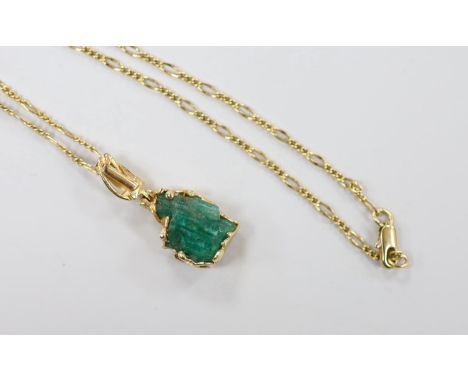 A yellow metal mounted carved emerald boulder set pendant, overall 34mm, gross weight 6 grams, on a gilt metal chain.