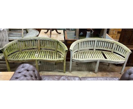 A pair of weathered teak 'banana' garden benches, length 158cm, depth 60cm, height 84cm (one with missing seat slat)