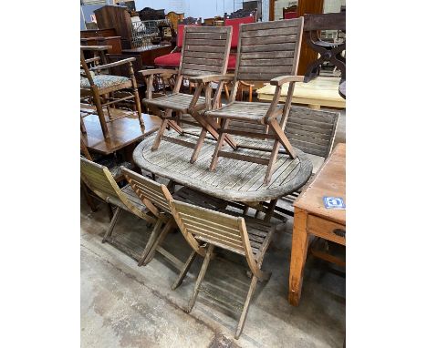 A weathered teak folding oval garden table, length 150cm, depth 91cm, height 74cm together with eight assorted chairs (2 carv