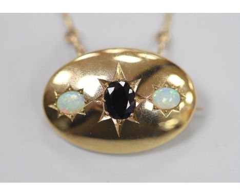 A 1970's 9ct gold and gypsy set single stone sapphire and two stone white opal set oval pendant brooch, 34mm, on a 9ct gold c