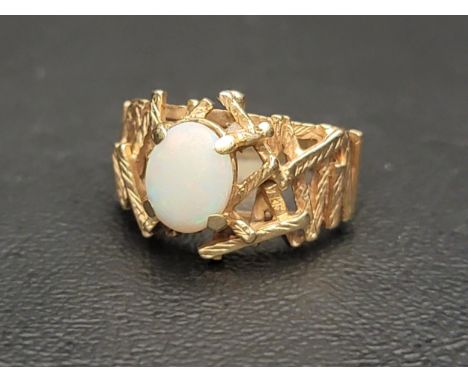 OPAL SINGLE STONE RINGthe oval cabochon opal flanked by abstract textured rod detail, in nine carat gold, Birmingham hallmark