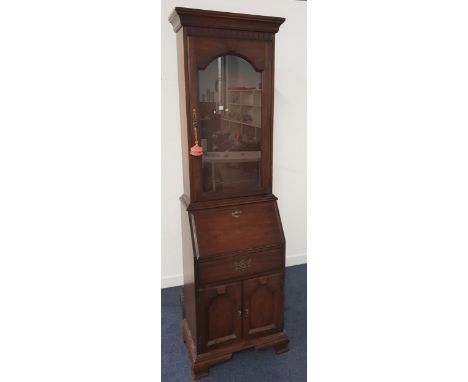 WALNUT BUREAU BOOKCASEwith a moulded top above a glass panelled door, the base with a fall flap opening to reveal a fitted in