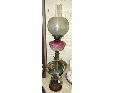 A late-Victorian oil lamp, the pink opaque glass reservoir with painted enamel floral decoration, on a reeded brass column an
