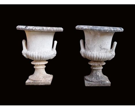 A pair of composition stone garden urns, of campana shape with a pair of handles with satyr masks, on a fluted socle, 72.5cm 