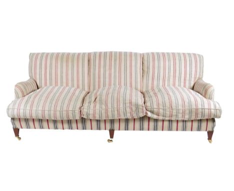 A Howard style three seater sofa, on square tapering front legs and brass castors, modern, 82cm high, 222cm wide, 89cm deep.