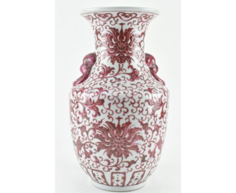 A 19th century ceramic vase decorated with blush pink over glazed enamelled foliage design. The vase with twin lion head hand