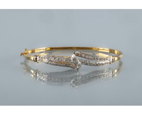 A DIAMOND STIFF HINGED BANGLE, the open scroll upper section pave set with numerous small round brilliants to a plain frame, 