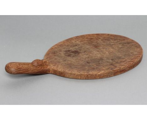 A ROBERT THOMPSON OAK CHEESE BOARD of oval form with carved mouse trademark in high relief to the handle, 15" long overall (E