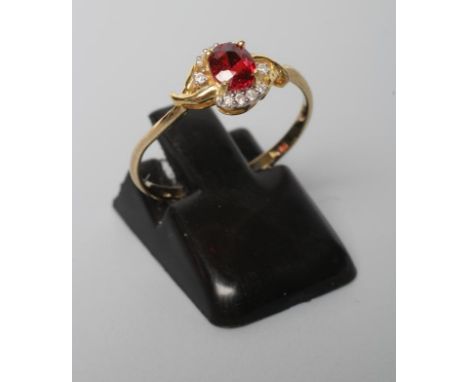 A RUBY AND DIAMOND RING, the oval facet cut ruby claw set to crossover shoulders point set with small round brilliant cut dia