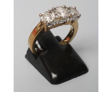 A THREE STONE DIAMOND RING, the round brilliants collet set in milled white mounts to a plain 9ct gold shank, Birmingham, siz