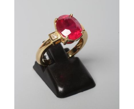 A RUBY RING, the oval facet cut stone of approximately 5.1cts claw set to square shoulders each with a small princess cut dia