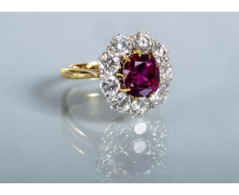 A RUBY AND DIAMOND CLUSTER RING, the oval facet cut ruby of approximately 3.76cts claw set to a border of nine brilliant cut 