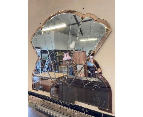 AN ART DECO SECTIONAL WALL MIRROR, fan shaped and cut with foliate scrolls, within an amber glass border surround, 54 1/2" x 