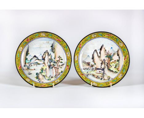 A PAIR OF CANTON ENAMEL SAUCER DISHES centrally painted in pastel colours with figures in extensive mountainous river landsca