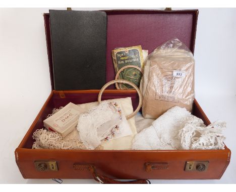 A quantity of early 20thC lace together with a sample book, embroidery hoops etc, in a vintage leather suitcase with label W.