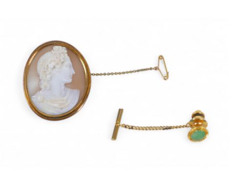 A cameo brooch with yellow metal mount, 3.5 by 4.3cm, 16.7g, and a 14ct gold and gilt metal tie pin with jade inlay, 4g. (2)