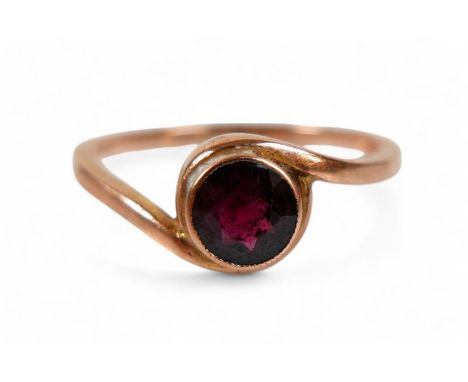 A 9ct rose gold and garnet ring, the round cut garnet measure approximately 5.5mm diameter, in a rub-over setting between two