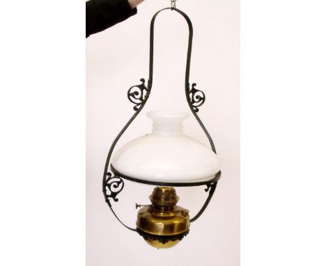 A brass hanging oil lamp with glass shade and wrought iron hanger 