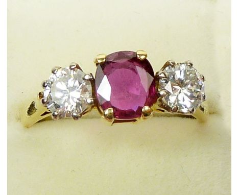 A fine 18ct gold three stone ruby and diamond ring,  the central oval cut ruby flanked by two brilliant cut diamonds, (accomp