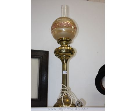 A tall brass oil lamp converted to electric with glass shade and funnel