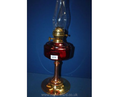A double wick paraffin Lamp with cranberry style glass reservoir and brass and copper base.