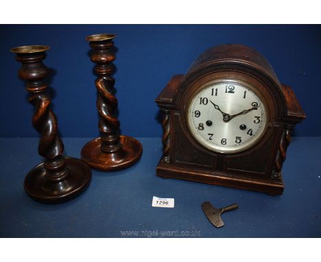 A mantle clock with barley twist detail an key and a pair of matching barley twist candlesticks