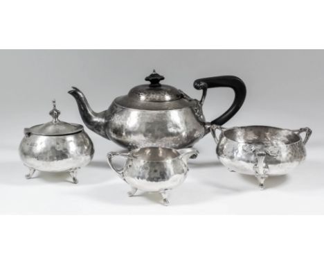 An Edward VII silver circular four piece tea service of bulbous form and with hammered finish and angular loop handles, on th