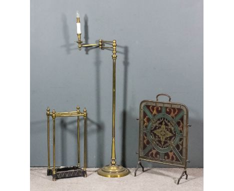 A brass electric standard lamp, the turned column with hinged adjustable branch terminating in electric candle fitment on cir