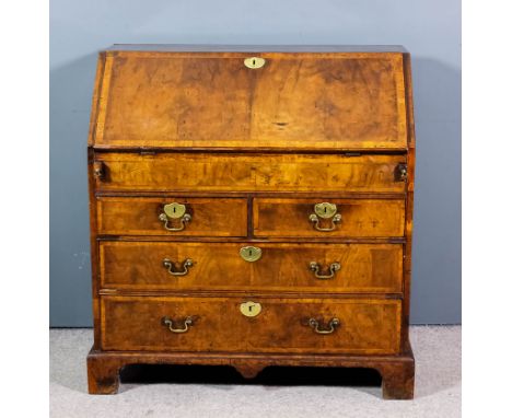 An 18th Century walnut bureau, the whole crossbanded and inlaid with stringings, the slope enclosing central cupboard enclose