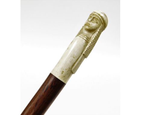 An early 20thC turned rosewood walking cane, with a carved ivory finial in the form of an Arab wearing headdress. 