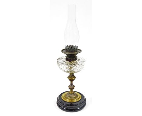 A 19thC brass oil lamp, with wrythen glass reservoir, on an black glazed circular foot, 61cm high. 