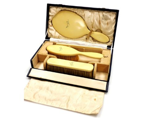 A Harrods of London ivorine dressing table set, comprising mirror, two brushes and a comb, each inscribed Joyce, in a fitted 