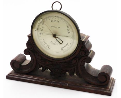 A late Victorian oak cased aneroid barometer by C. Baker, 244 High Holborn London, the circular dial on scroll and leaf carve