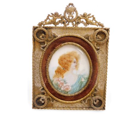 An early 20thC portrait miniature, of a lady in oval frame, with red hair and blue flowing dress, the gilt frame with harp an