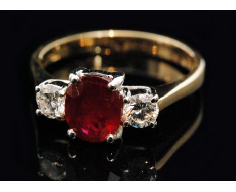 A hallmarked 18ct ruby and diamond three stone ring, central oval cut ruby claw set with two brilliant cut diamonds to knife 