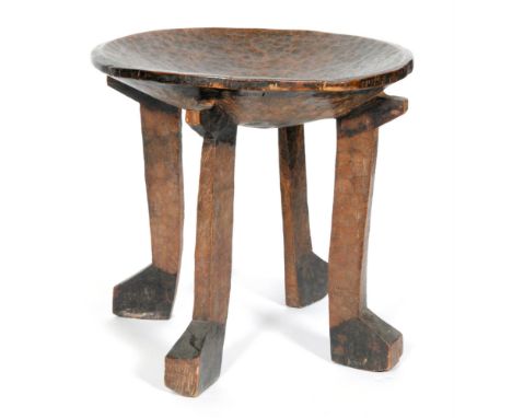 An African tribal hardwood stool of dished circular form, possibly East African, raised to four strut type legs with club sha