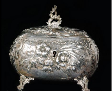 An Austrian silver embossed tea caddy of oval form with hinged lid, embossed with floral and scrollwork decoration, on four s