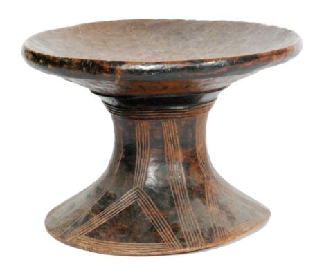 An African tribal hardwood stool of waisted circular form, the splayed circular base with scored line decorative detail, sten