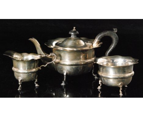 A hallmarked silver three piece tea service composed of teapot, sugar bowl and cream jug, each with wavy rim and central gird