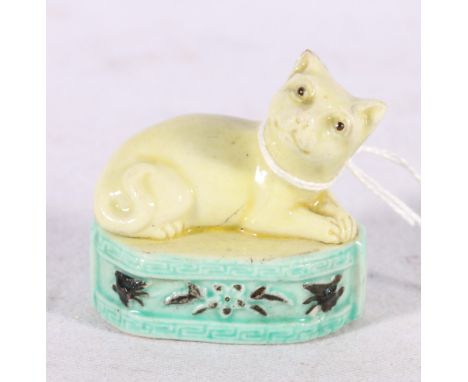 Small Chinese porcelain model of a cat on a relief moulded plinth base, yellow, black and turquoise glazed, 5cm. 