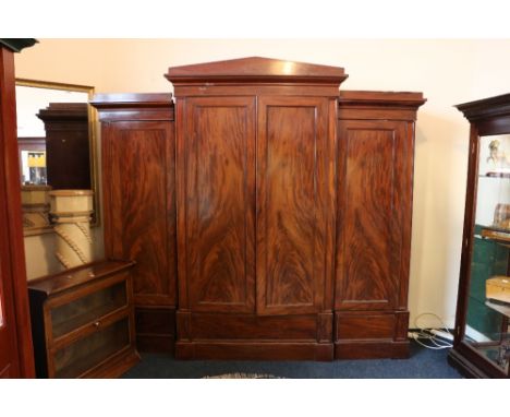 Victorian mahogany breakfront four-door wardrobe with architectural arch pediment above four flame cut panel doors raised on 