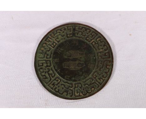 Chinese bronze mirror with incised decoration of fish surrounded by stylised symbols and a deep scrolling border, 13cm, woode