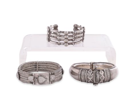 THREE INDIAN SILVER BANGLES
One hinged hollow-formed example with rounded exterior and screw clasp; a quad-strand rope-link e