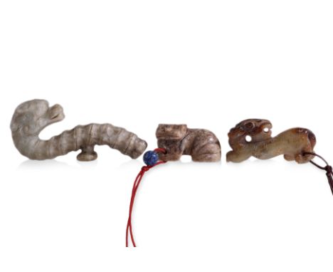 A GROUP OF THREE JADE CARVINGS (1) Comprising a dragon form belt-hook, a celadon and russet toned recumbent beast, and a beig